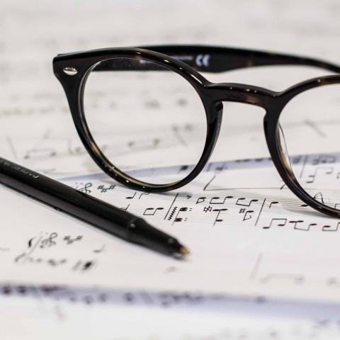 Glasses and pen resting on sheet music