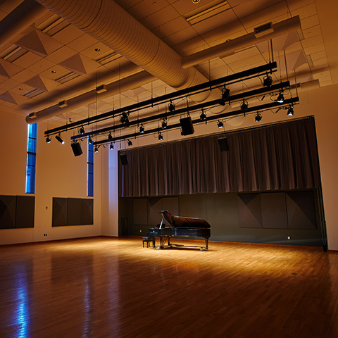 A piano is spotlighted in the middle of studio 106