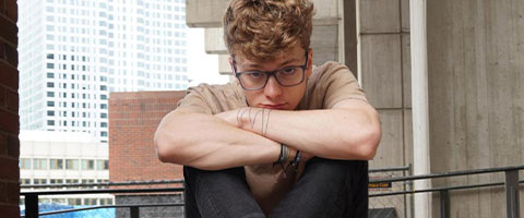 Kieran rhodes sitting on a balcony and staring at the camera