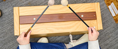 Aerial shot of a child's hands playing a wooden percussion instrument