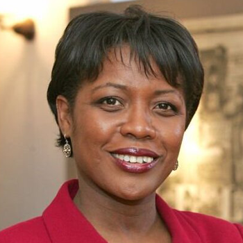 Headshot of Tracy Gibbs, wearing a red blazer and smiling.