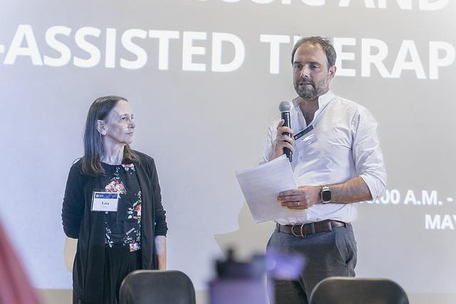 An image of presenters speaking at a conference. 
