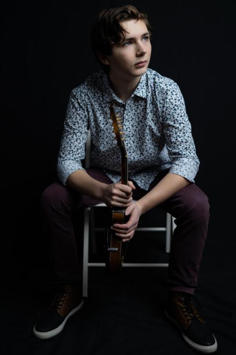 seated man in a button-down shirt holding a mandolin