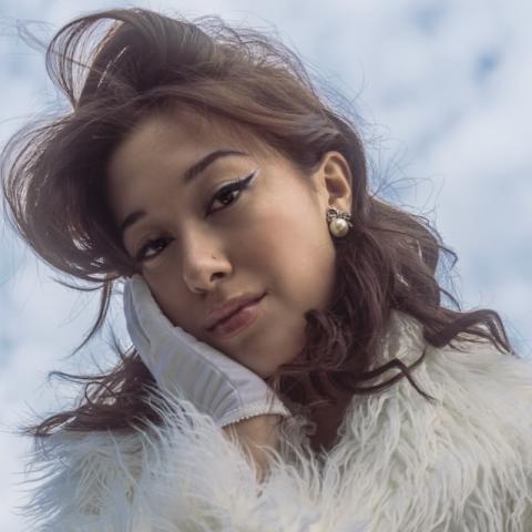Headshot of Lili Chey Warren with clouds in the background and wind through her hair