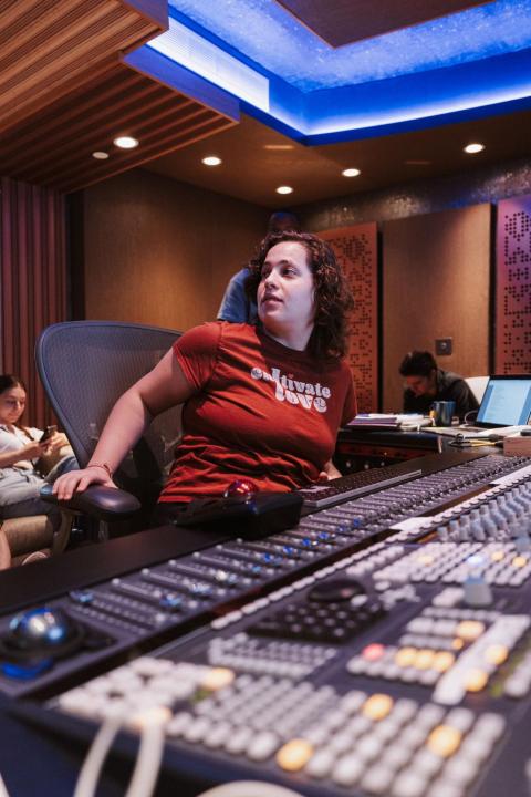 a woman sitting at a recording studio console